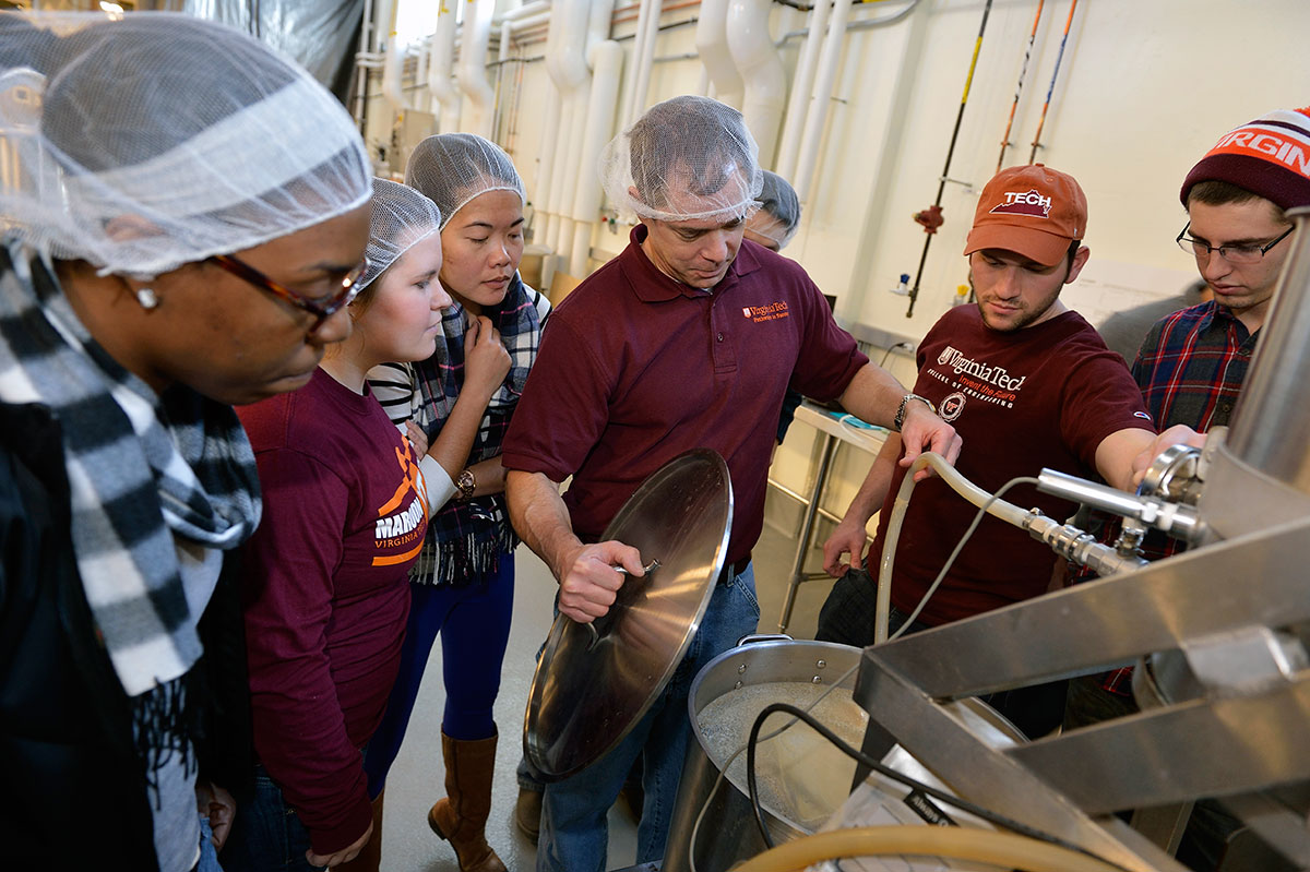 Plant manager and Virginia Tech students check a batch of beer in the brewhouse