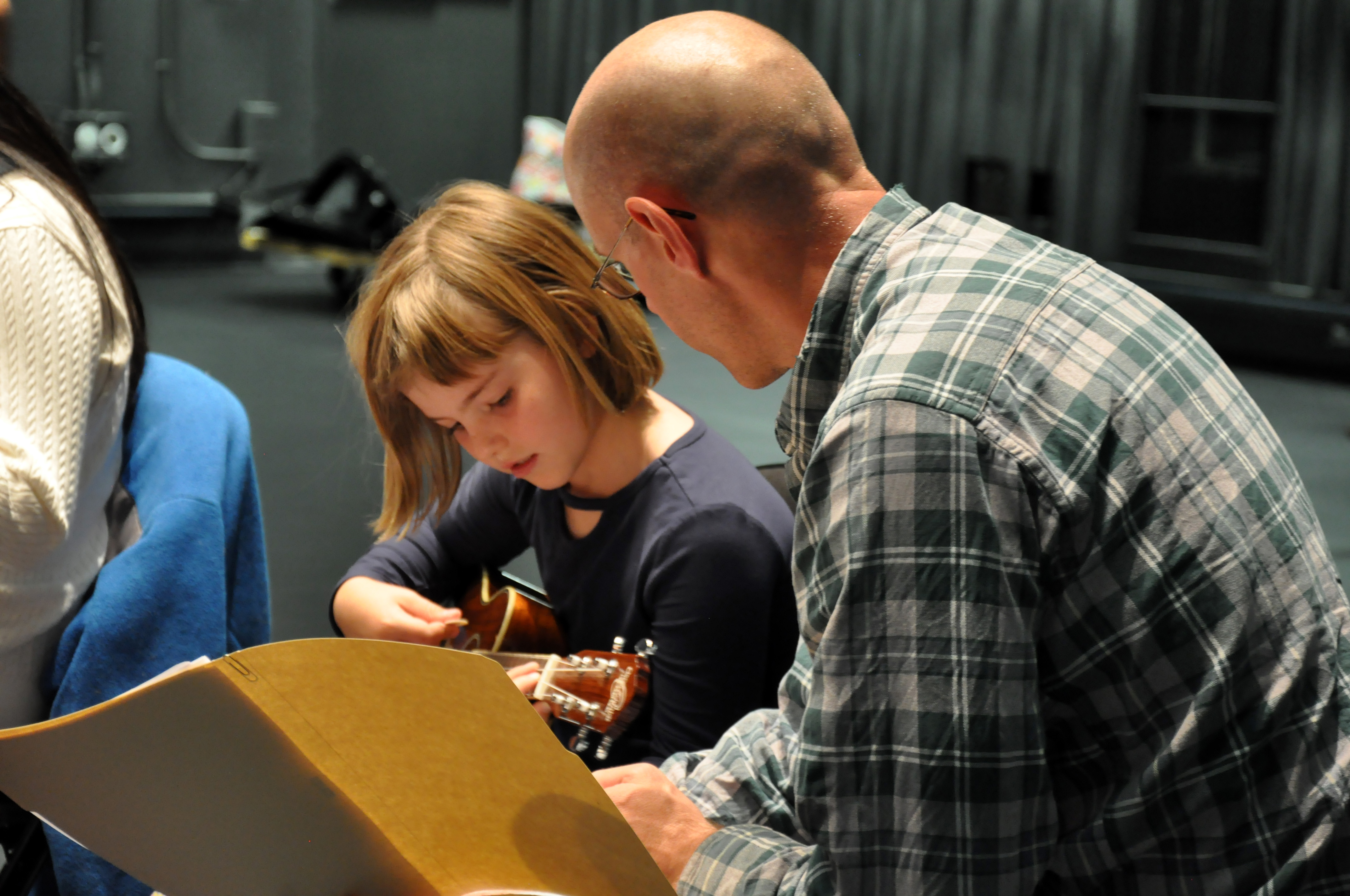 person working with a young girl with a guitar