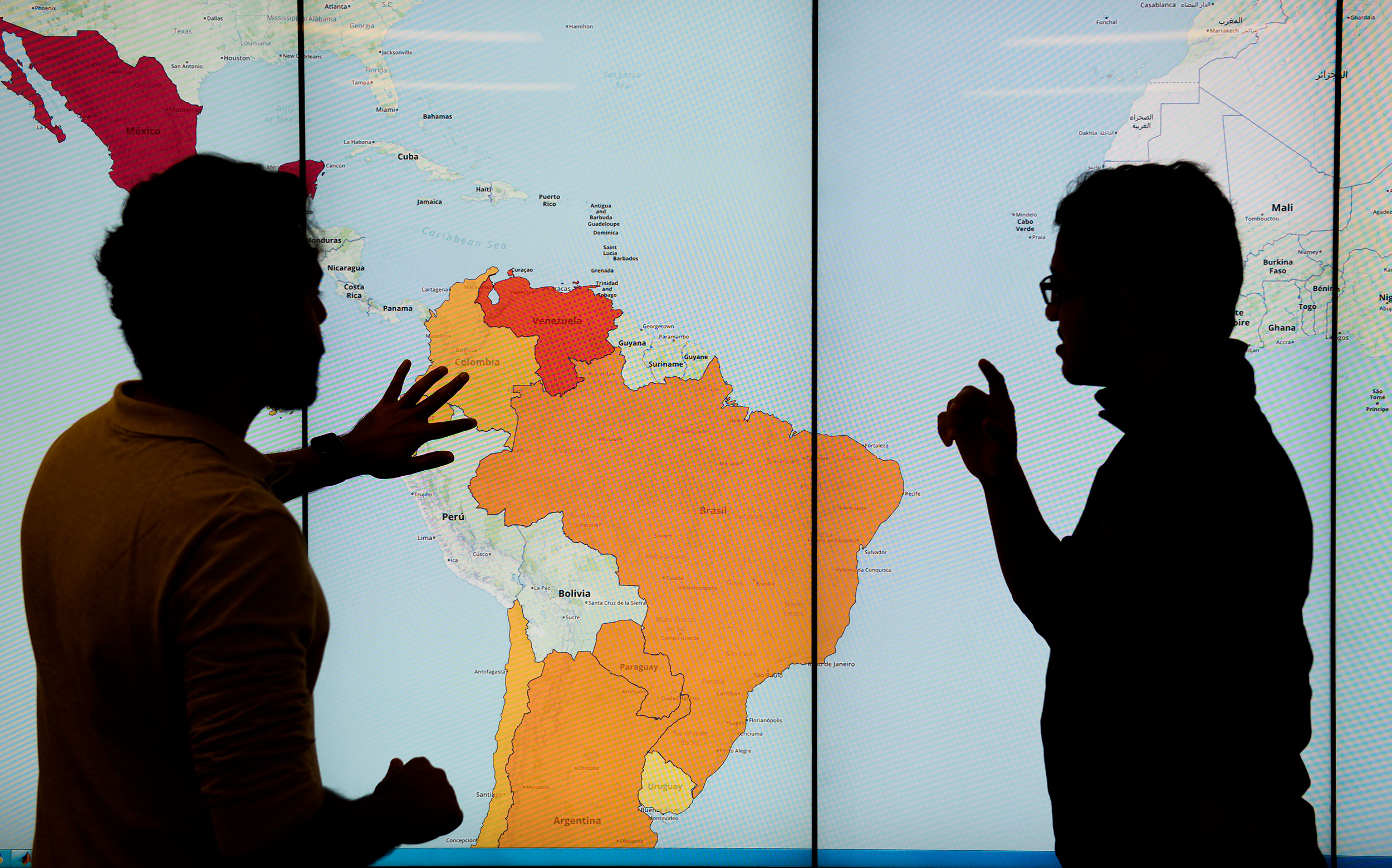 Graduate students in the Discovery Analytics Center with displays from the EMBERS Project at Virginia Tech's Arlington Research Center. EMBERS is a system for forecasting societal significant societal events from open source surrogates.