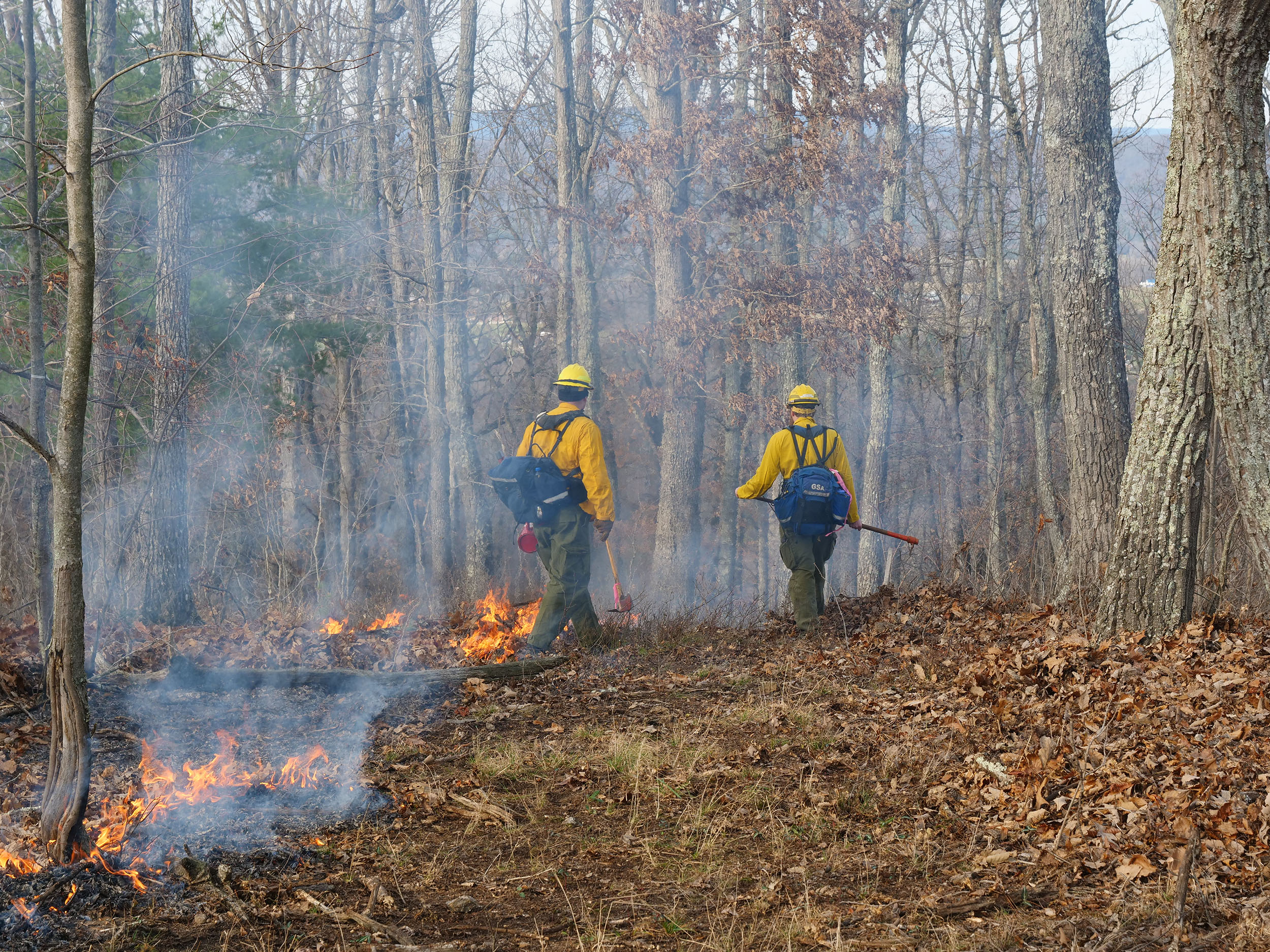 Crew members patrol the fire line with shovels and rakes to ensure that no flames or embers escape the established perimeter