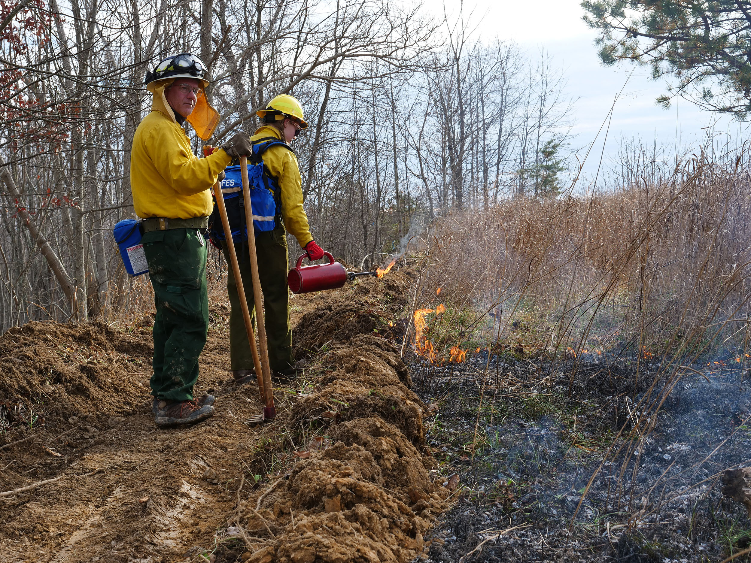 Dennis McCarthy (left) of the Virginia Department of Forestry advises student Emily Newcombe on techniques for igniting along the fire perimeter
