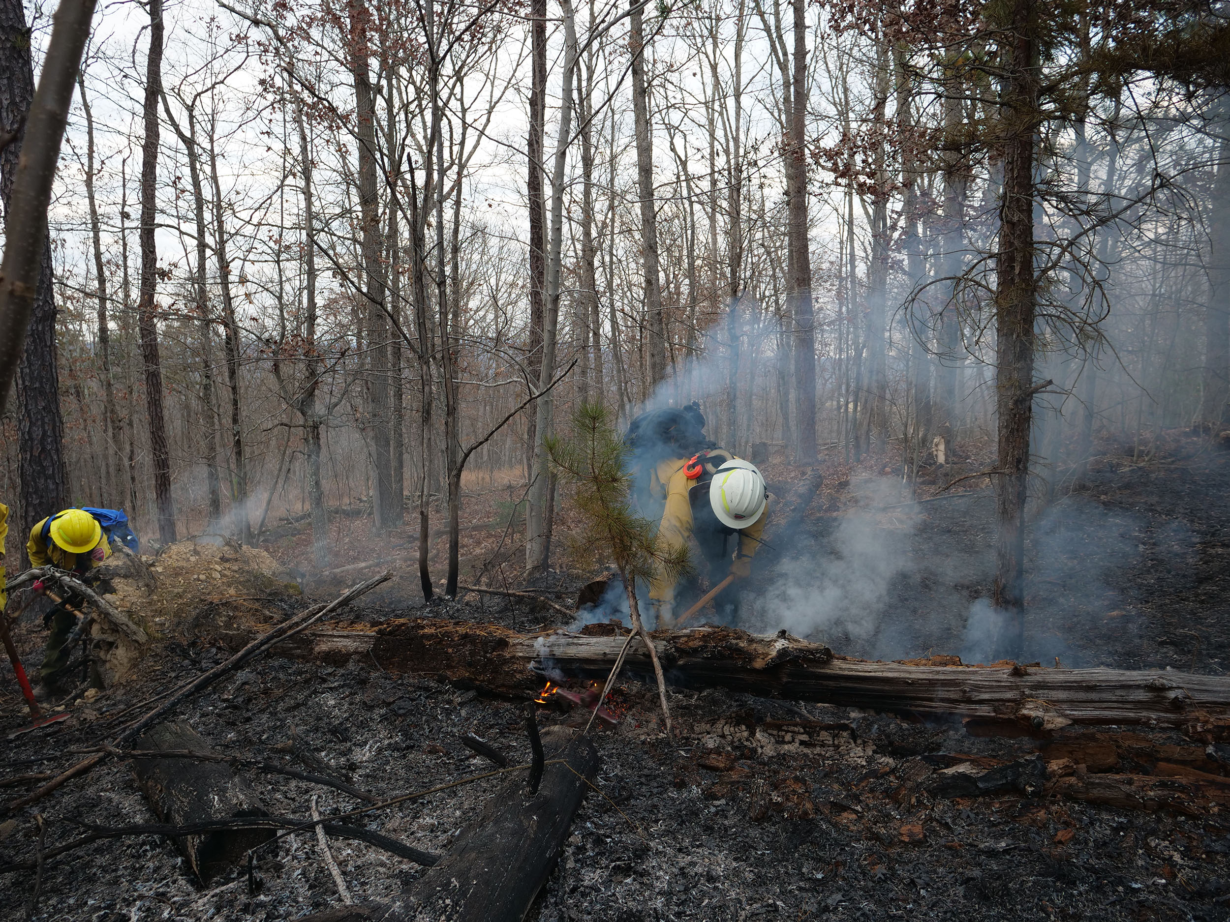 Crew members monitor large debris for smoldering even after the flames are extinguished